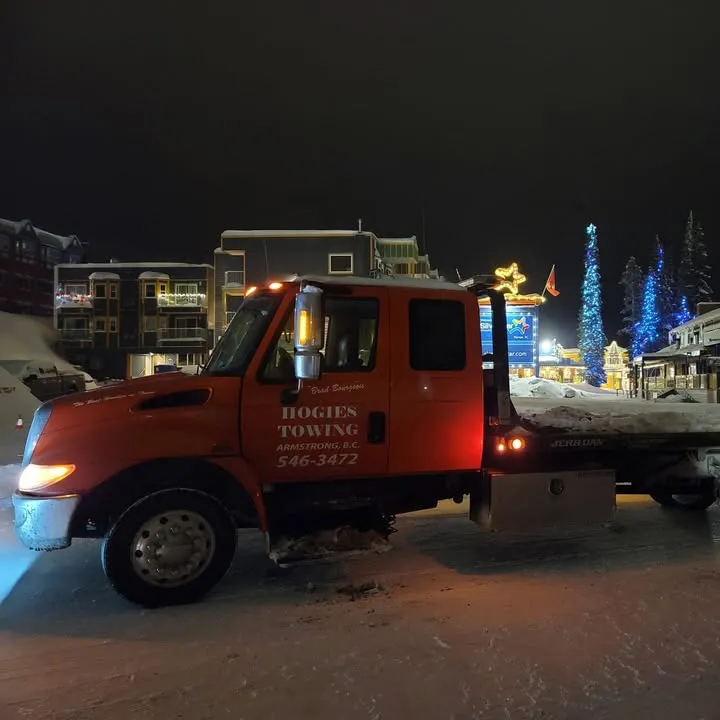 Hogie's orange deck truck parked in SilverStar village at night, Christmas lights behind