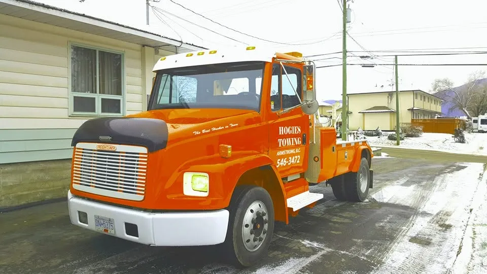Hogie's Towing orange wrecker truck with The Best Hooker in Town painted on the hood